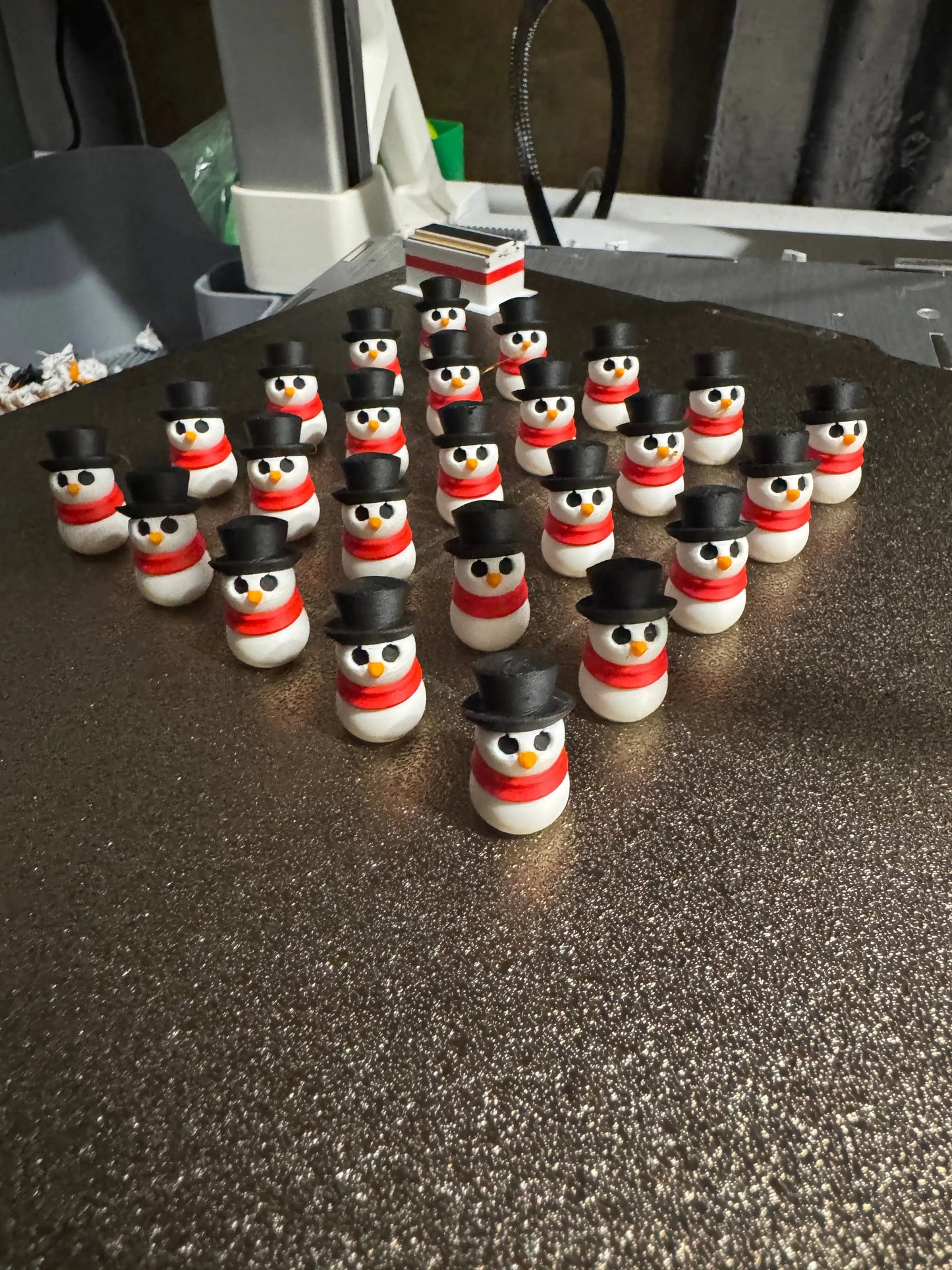 snowman-shaped objects with black top hats and red scarves on a metallic plate