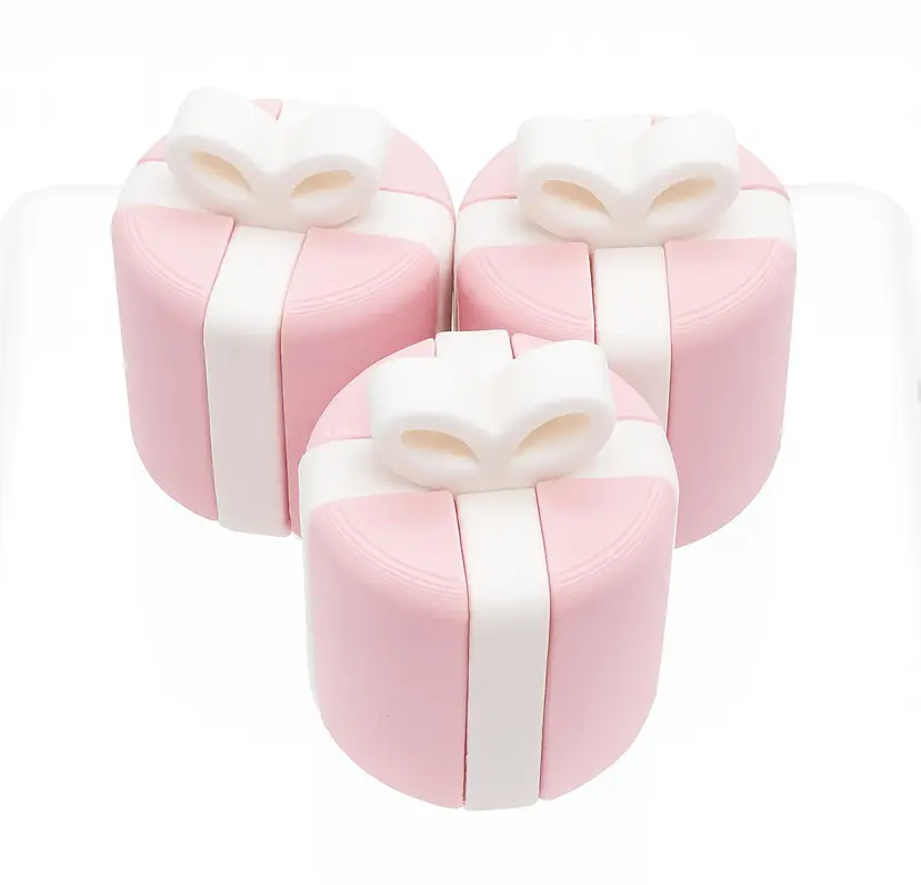Set of three pink gift box-shaped cushions with white ribbons on a white background